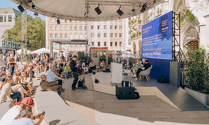 Öffentliche Veranstaltung mit Podiumsdiskussion auf dem Münchner Marienplatz im Jahr 2023, an dem auch das MCube Cluster beteiligt war.