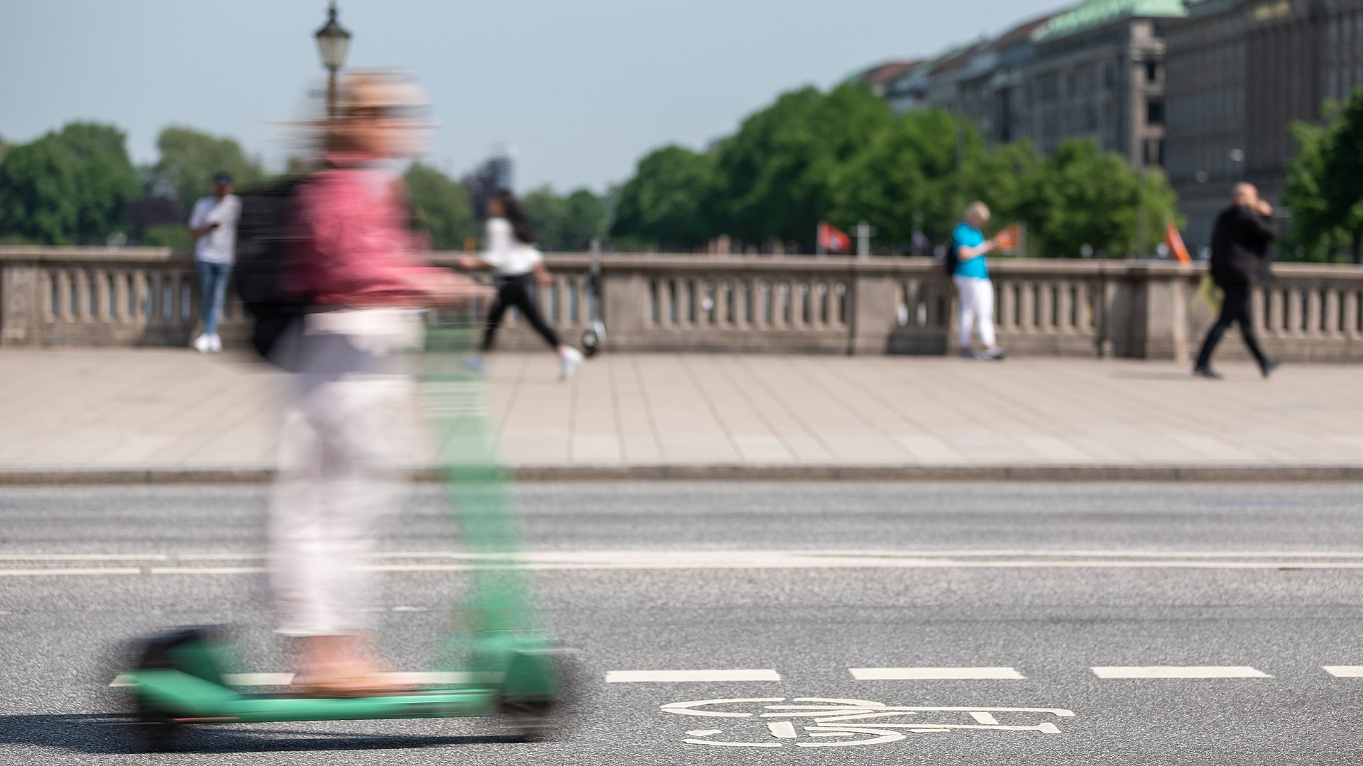 A person rides an e-scooter over a bridge A person rides an e-scooter over a bridge