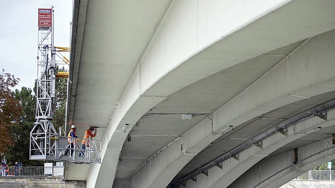 Zwei Forschende installieren Ultraschall-Sensoren an der Unterseite der Gänstorbrücke zwischen Ulm und Neu-Ulm 