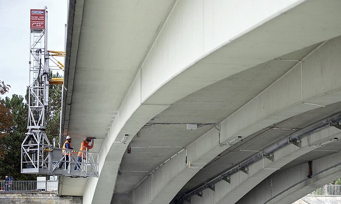 Zwei Forschende installieren Ultraschall-Sensoren an der Unterseite der Gänstorbrücke zwischen Ulm und Neu-Ulm 