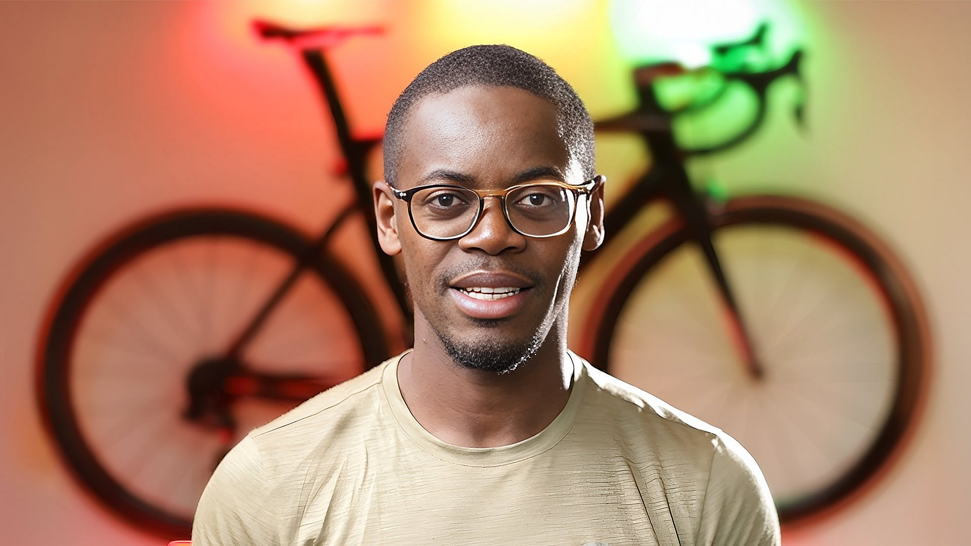 10.000 Kilometer für die Bildung Porträtfoto von Emmanuel Adjei, im Hintergrund ein illuminiertes Fahrrad