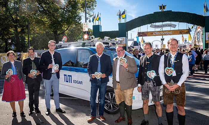 Geladene Gäste vor dem Wiesn Shuttle, im Hintergrund ist das Oktoberfest zu sehen