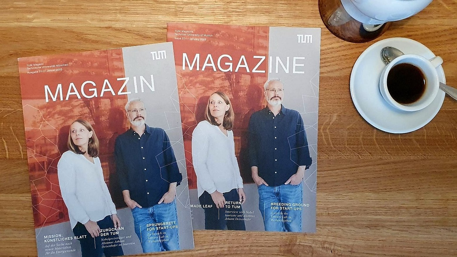  Two issues of the new magazine of the Technical University of Munich (TUM) on a wooden table, with coffee crockery next to it