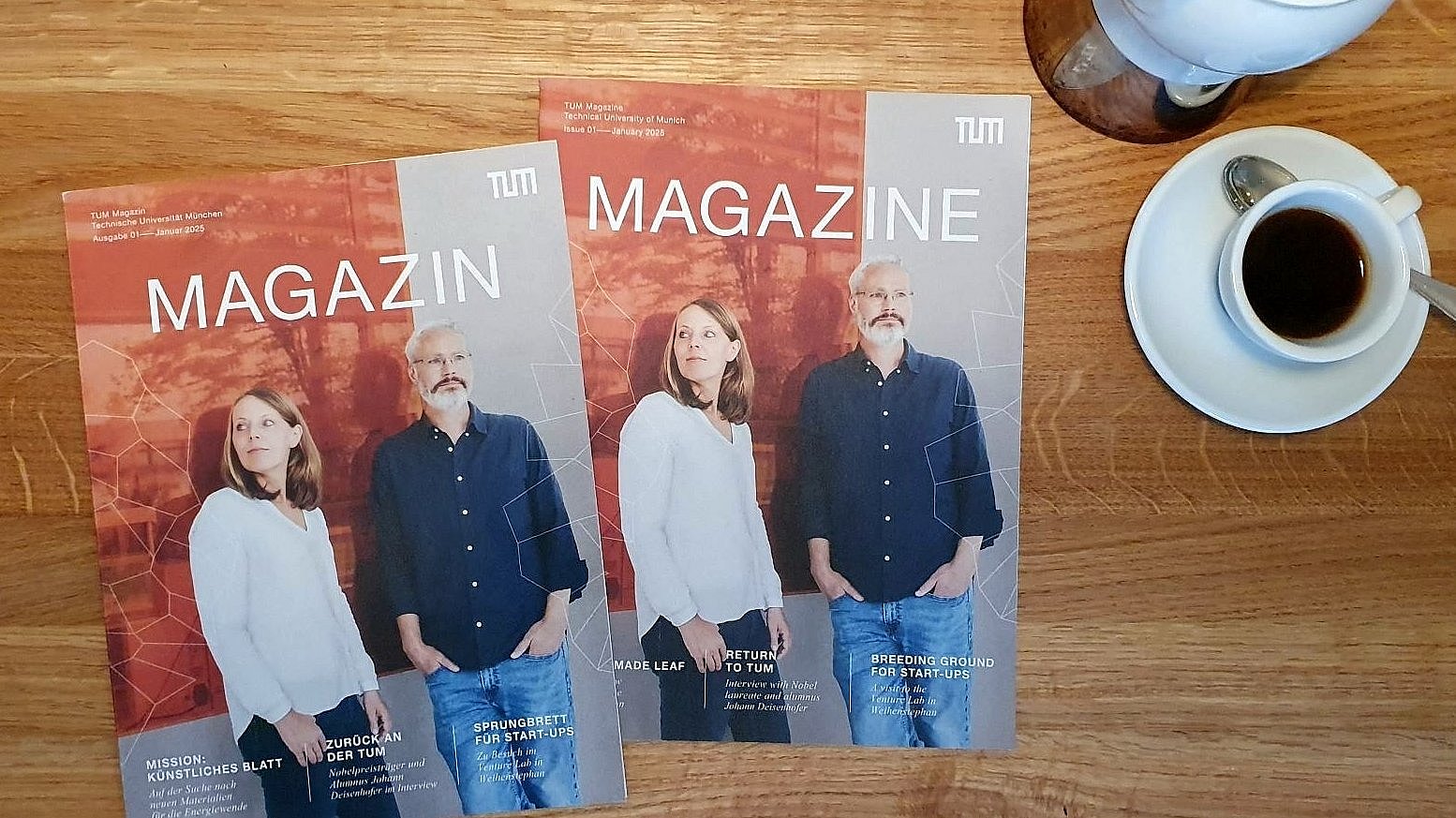  Two issues of the new magazine of the Technical University of Munich (TUM) on a wooden table, with coffee crockery next to it