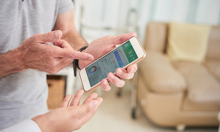 An elderly person discusses health data on a smartphone with a doctor.