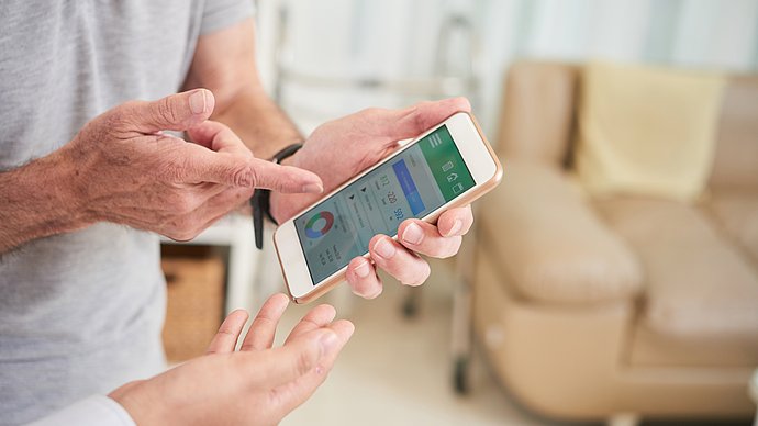 An elderly person discusses health data on a smartphone with a doctor.