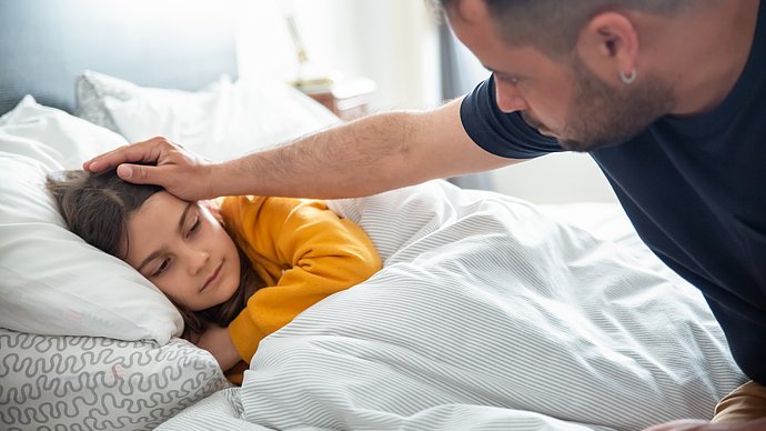 Copilot  A sick child in bed is being comforted by an adult.