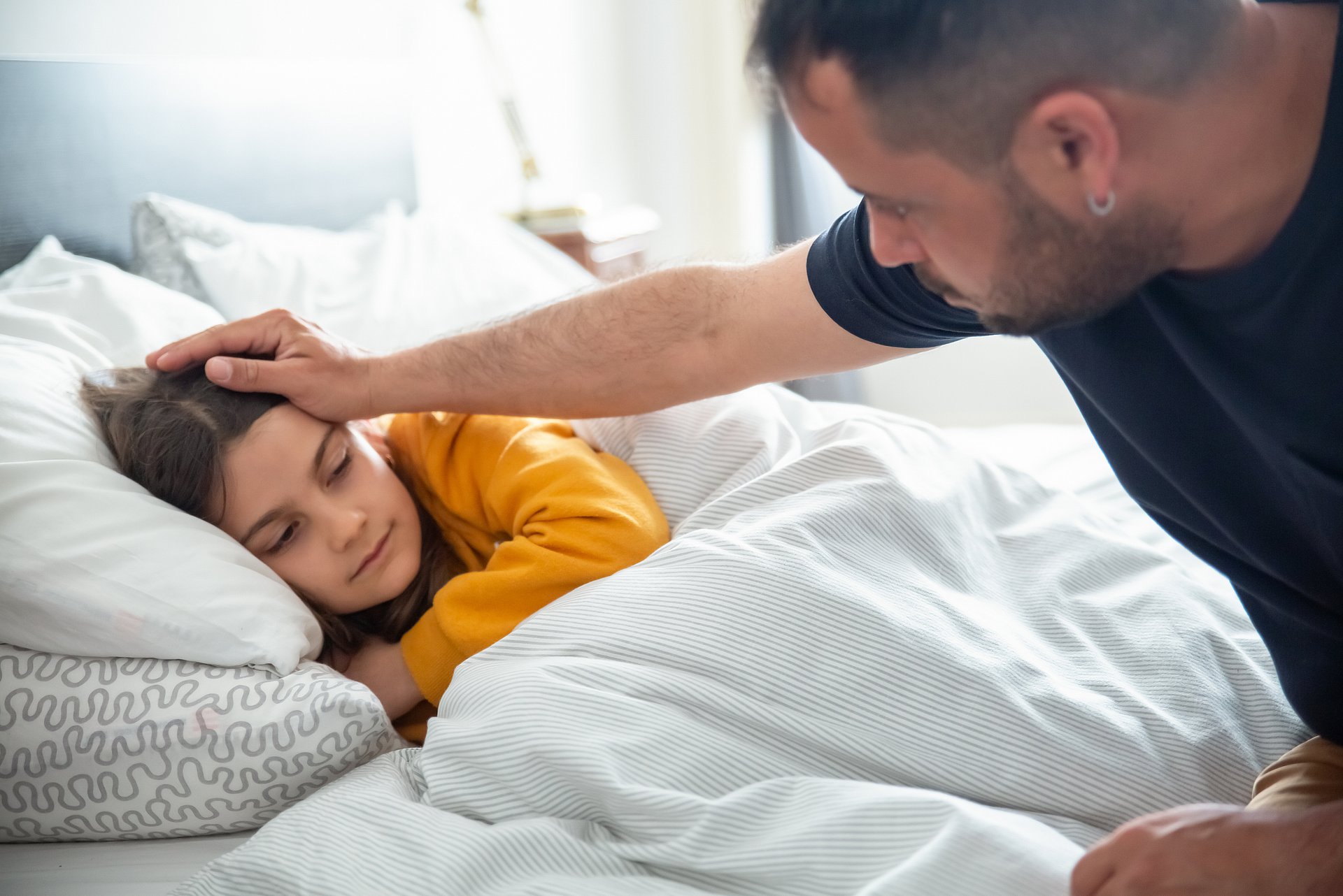 Copilot  A sick child in bed is being comforted by an adult.