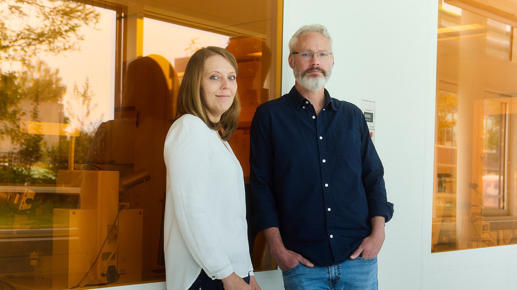 Johanna Eichhorn und Ian Sharp vor einer Wand mit orangefarbenen Scheiben