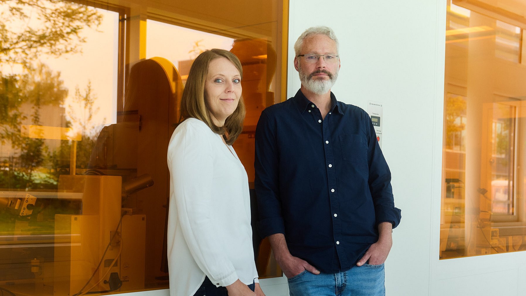 Johanna Eichhorn und Ian Sharp vor einer Wand mit orangefarbenen Scheiben