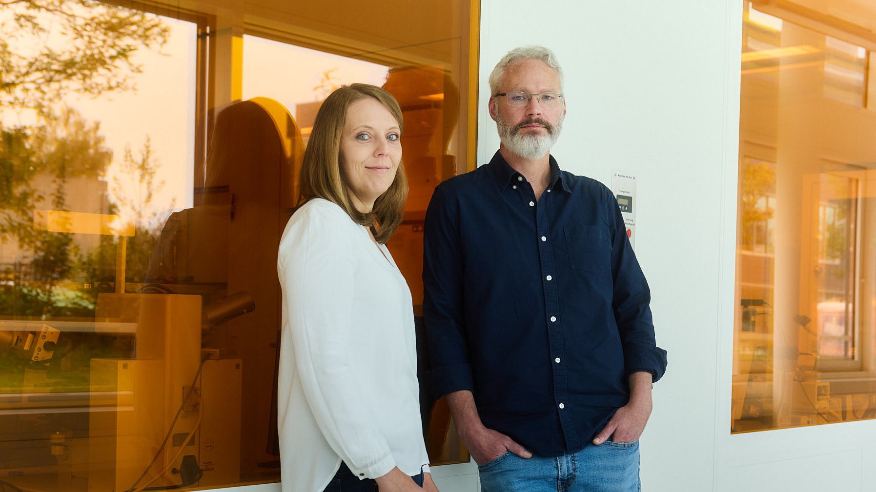 Johanna Eichhorn und Ian Sharp vor einer Wand mit orangefarbenen Scheiben