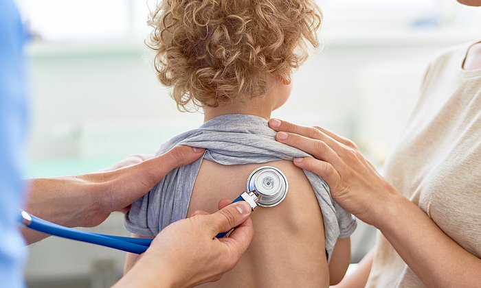 a doctor examining the lungs of a child with a stethoscope