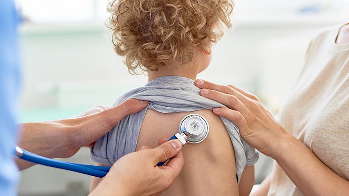 a doctor examining the lungs of a child with a stethoscope