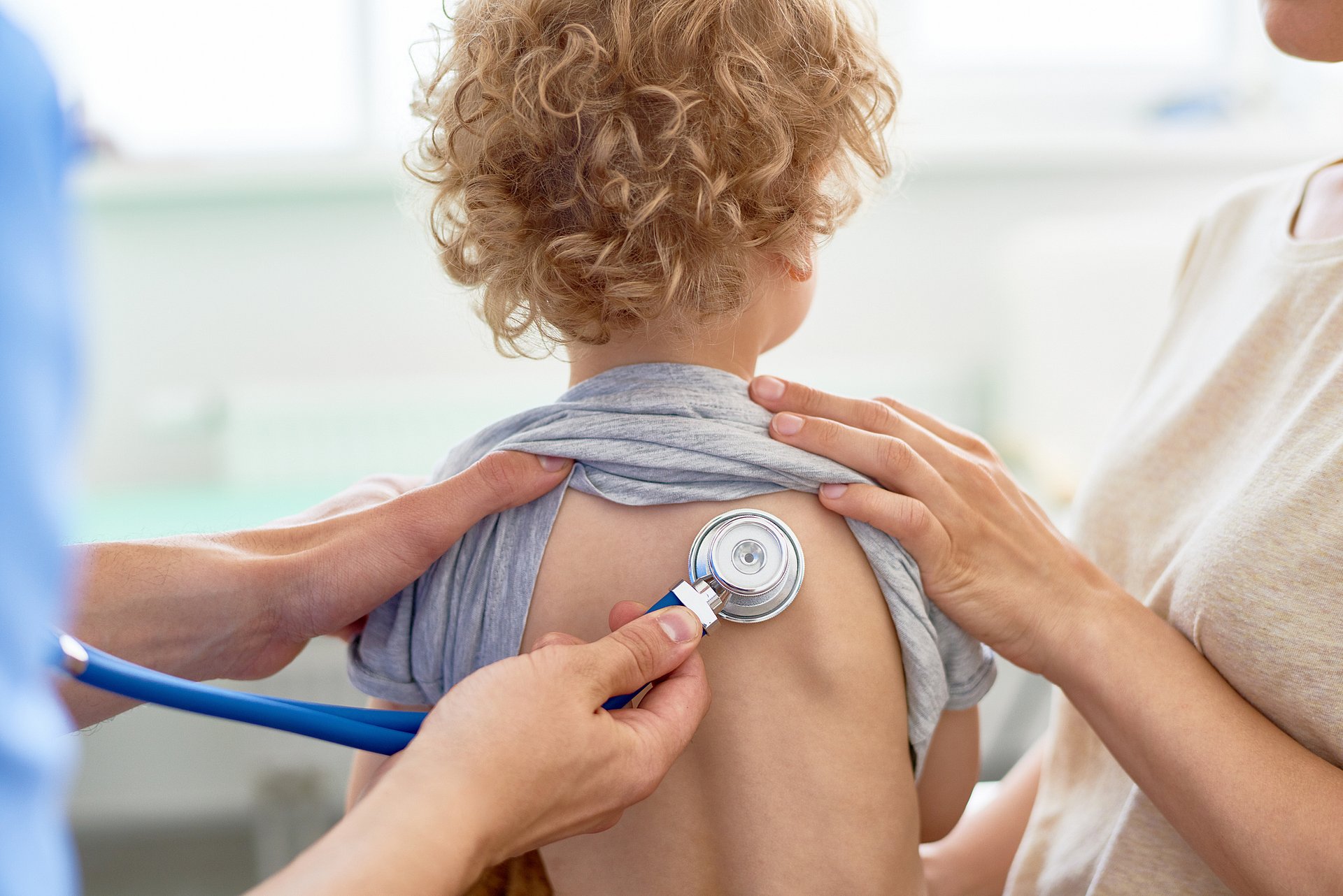 a doctor examining the lungs of a child with a stethoscope