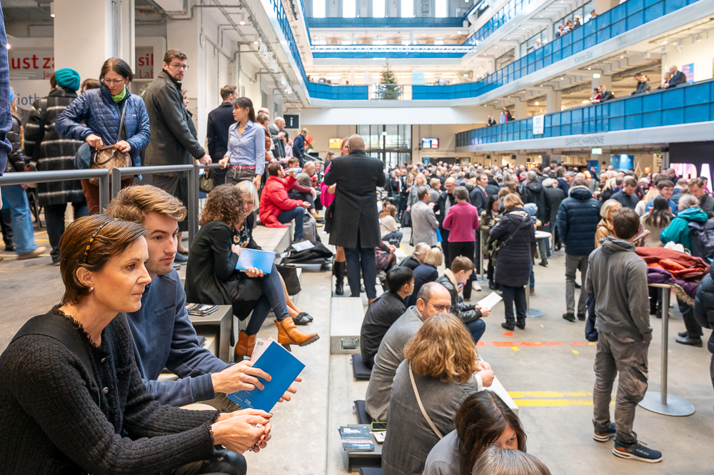 Many guests wait for admission to the concert hall, some sitting on the large steps, some standing