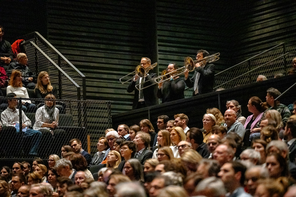 three brass players play in the auditorium